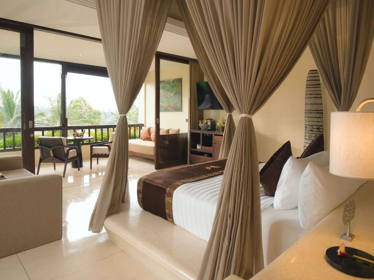 Jungle View Royal Suite bedroom with canopy bed, living area, and private balcony views in Ubud, Bali