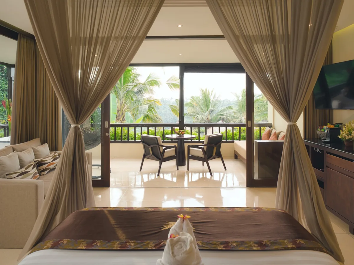 Jungle View Royal Suite with canopy bedroom, living area, and private balcony overlooking the rainforest in Ubud, Bali
