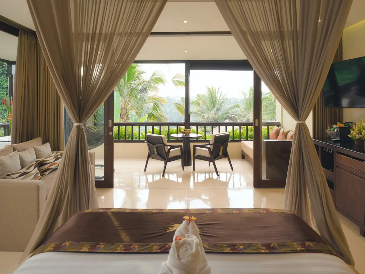 Panoramic Corner Jacuzzi Royal Suite bedroom with private balcony, living area, and jungle views in Ubud, Bali
