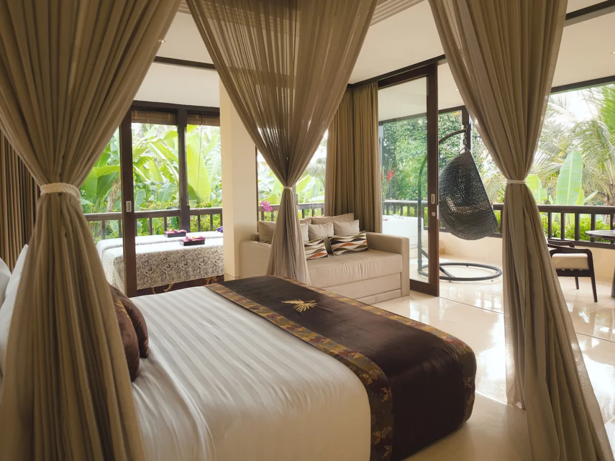 Panoramic Corner Jacuzzi Royal Suite bedroom with living area, private balcony, and tropical views in Ubud, Bali