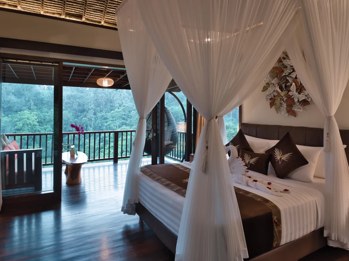 Sunrise View Villa bedroom with canopy bed, private balcony, and lush rainforest views in Ubud, Bali