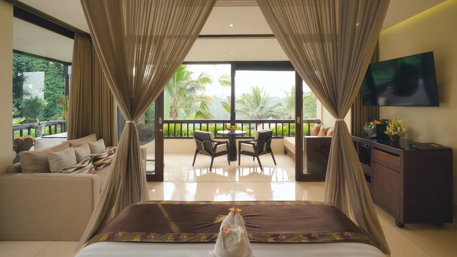 Jungle View Royal Suite with canopy bedroom, living area, and private balcony overlooking the rainforest in Ubud, Bali