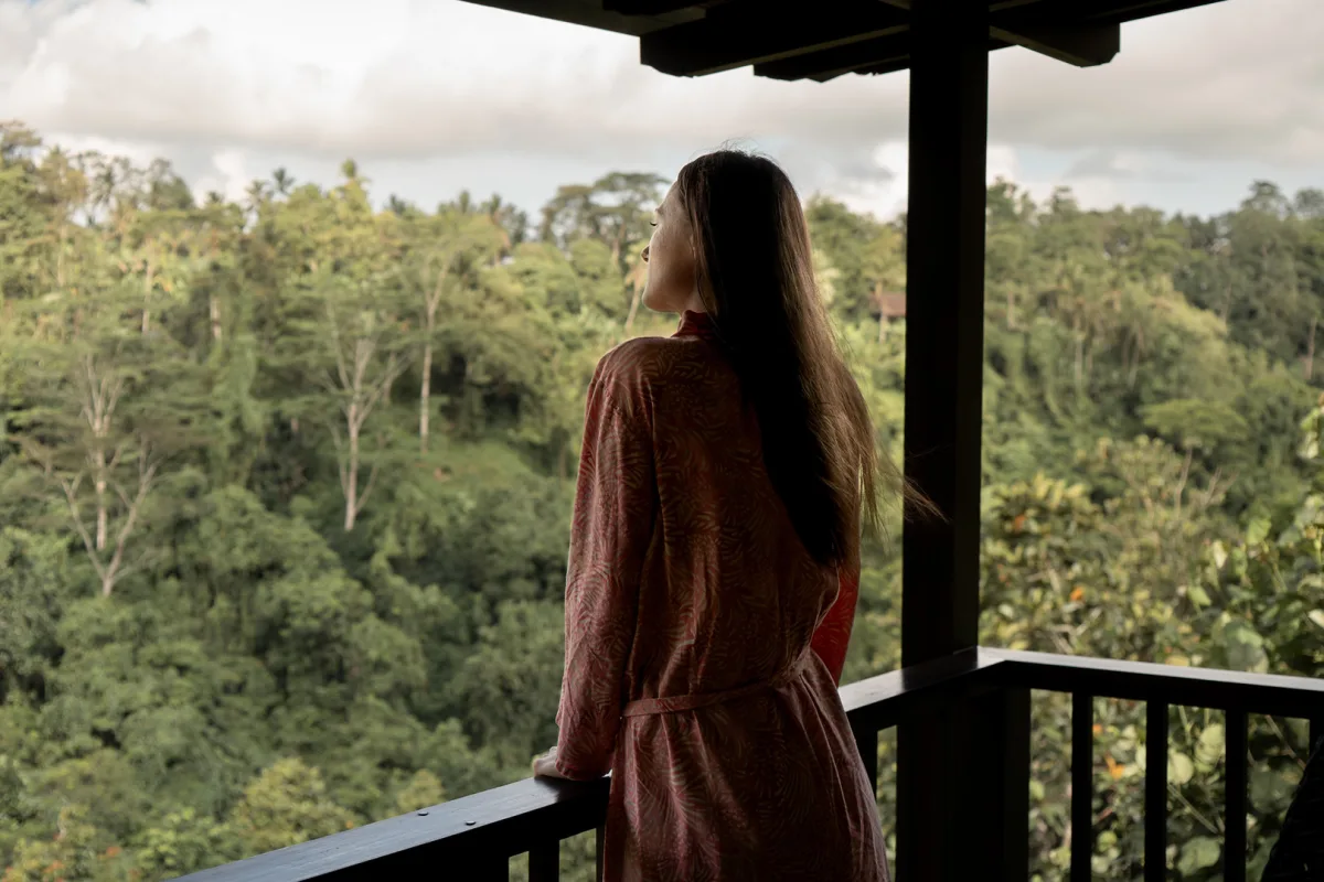 Guest overlooking the jungle view from a balcony at Nandini Jungle by Hanging Gardens in Bali.