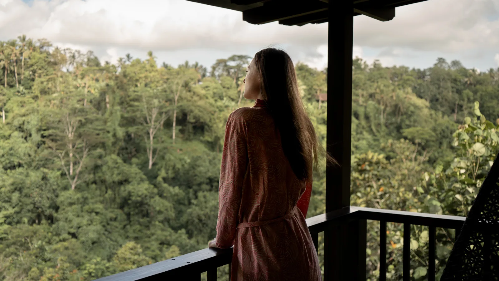 Guest overlooking the jungle view from a balcony at Nandini Jungle by Hanging Gardens in Bali.