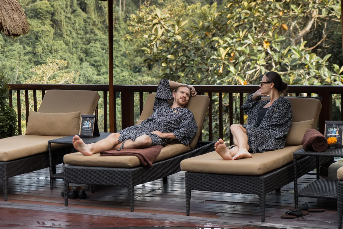 Couple relaxing on poolside loungers during a day pass at Nandini Jungle by Hanging Gardens in Bali.