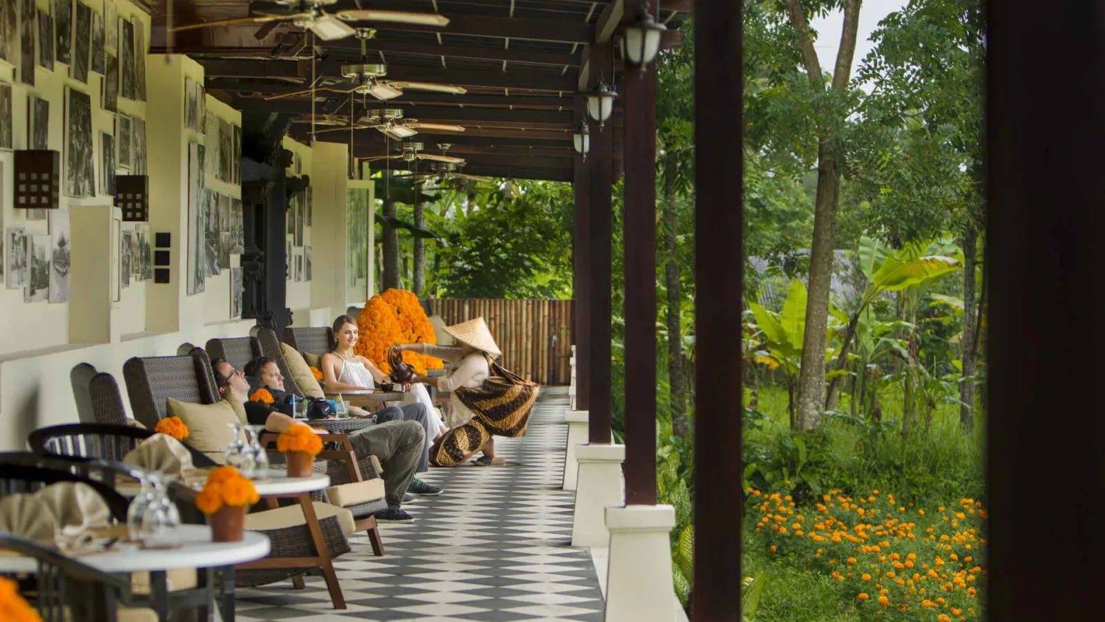 Guests relaxing at the Heritage Lounge terrace with a Balinese dancer surrounded by lush jungle at Nandini Jungle by Hanging Gardens Bali.