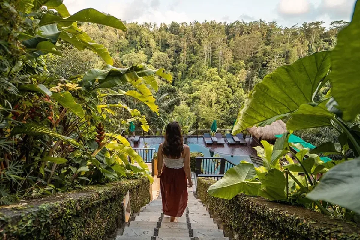 Guest walking through the tropical jungle surroundings at Nandini Jungle by Hanging Gardens in Ubud, Bali
