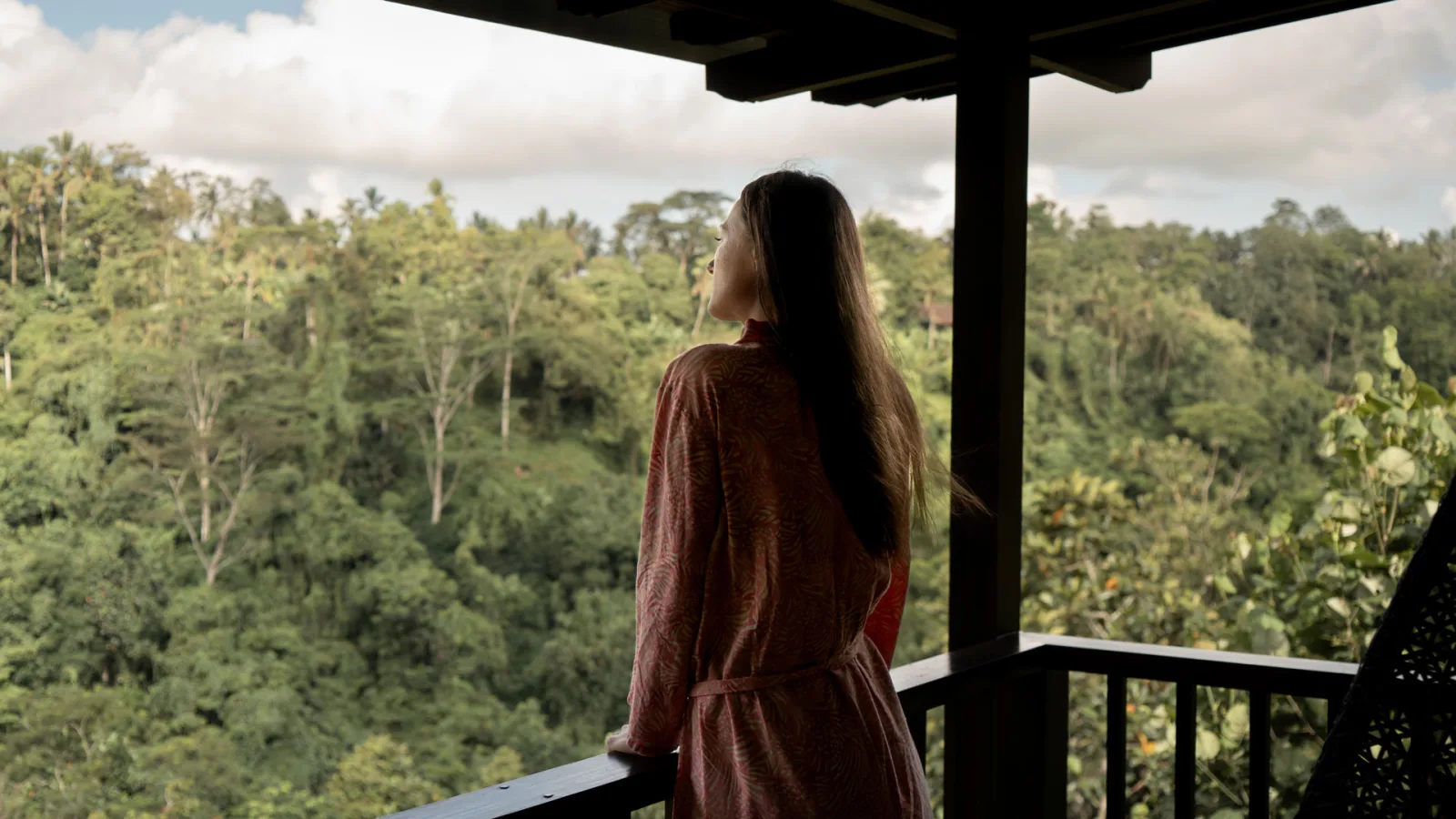 Woman enjoying panoramic jungle views from a private balcony at Nandini Jungle by Hanging Gardens in Ubud