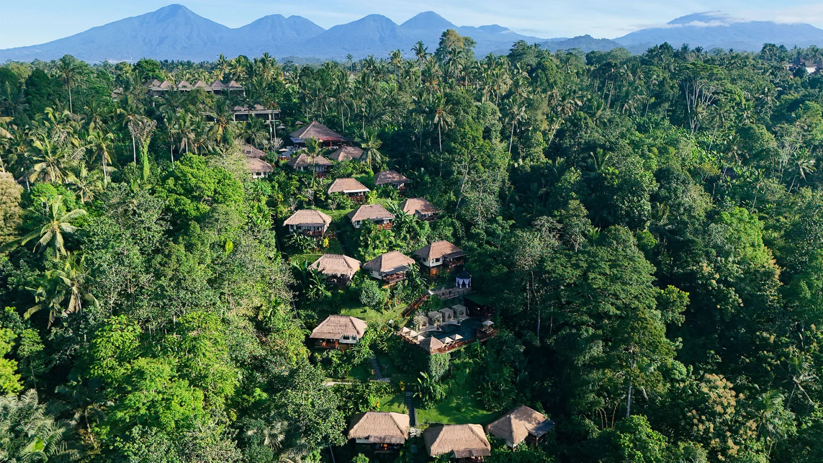 Aerial view of Nandini Jungle by Hanging Gardens, featuring luxury villas surrounded by lush tropical rainforest and scenic mountains in Ubud, Bali.